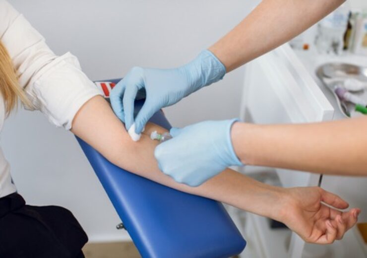 Close up cropped image of unrecognizable doctor and patient. Lab technician nurse pierces the patient's arm vein with needle to collect blood into tube. Blood analysis, donation, dna.