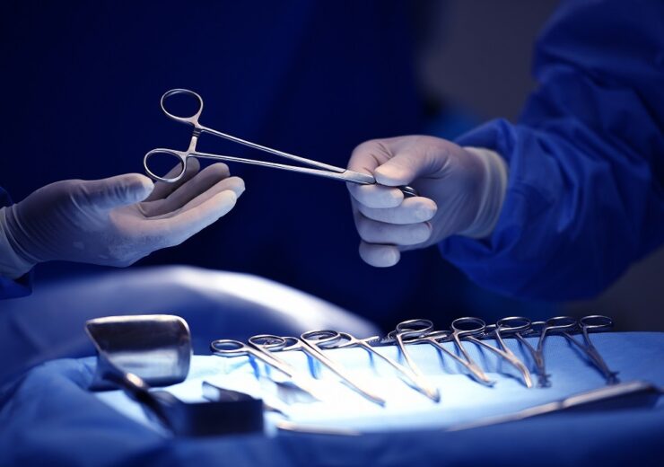 Surgeon hand picking up an instrument from tray of surgical inst